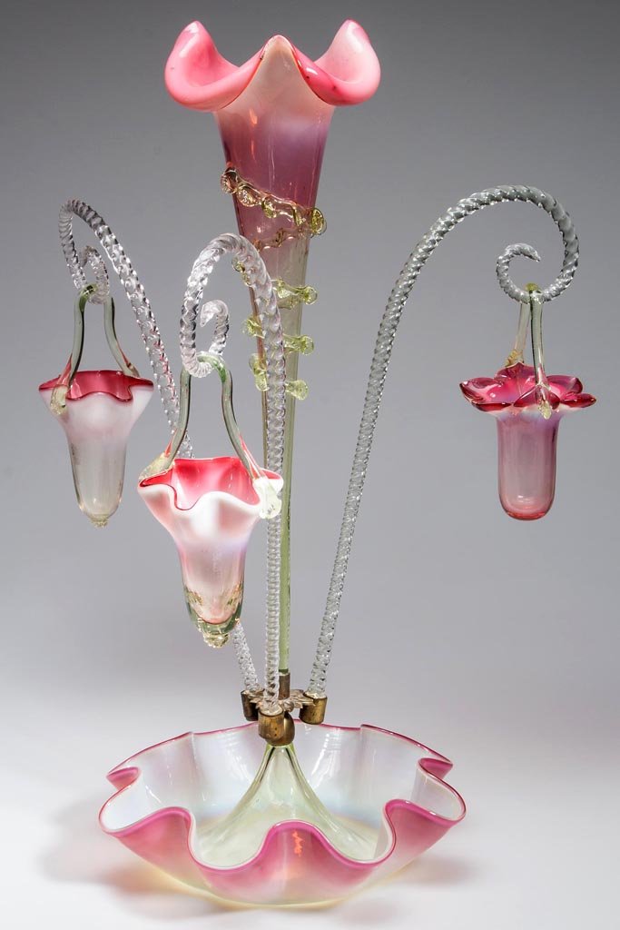 VICTORIAN GLASS EPERGNE: VICTORIAN GLASS EPERGNE, cranberry opalescent to pale green, ruffle-edge bowl supporting a central lily-form vase with applied rigaree, centering three twisted shepherd hooks each supporting a basket.