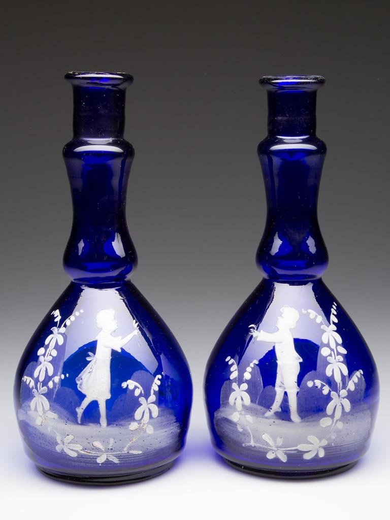 MARY GREGORY (SO-CALLED) PAIR OF BITTERS / BARBER'S: MARY GREGORY (SO-CALLED) PAIR OF BITTERS / BARBER'S BOTTLES, cobalt blue, light rib-optic pattern to each, white enamel girl and boy figures within landscapes, each with a rough pontil mark. Late 19th