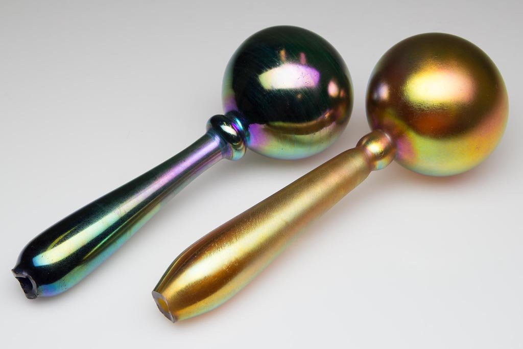 STEUBEN AURENE DARNING BALLS, LOT OF TWO: STEUBEN AURENE DARNING BALLS, LOT OF TWO, gold iridescent and blue iridescent, each with rough open pontil end, not signed. Steuben Glass Works. Circa 1910-1925. 7" and 7 1/2" L. Literature: Dimitroff