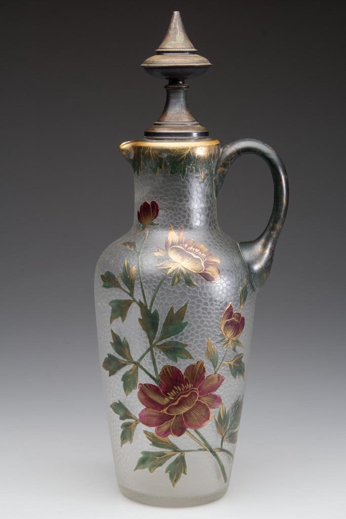 EUROPEAN ACID CUT-BACK AND ENAMELED JUG: EUROPEAN ACID CUT-BACK AND ENAMELED JUG, gilt highlights, colorless textured ground decorated with flowers and leaves, applied handle, polished pontil mark, original stopper with silver mount bearing 