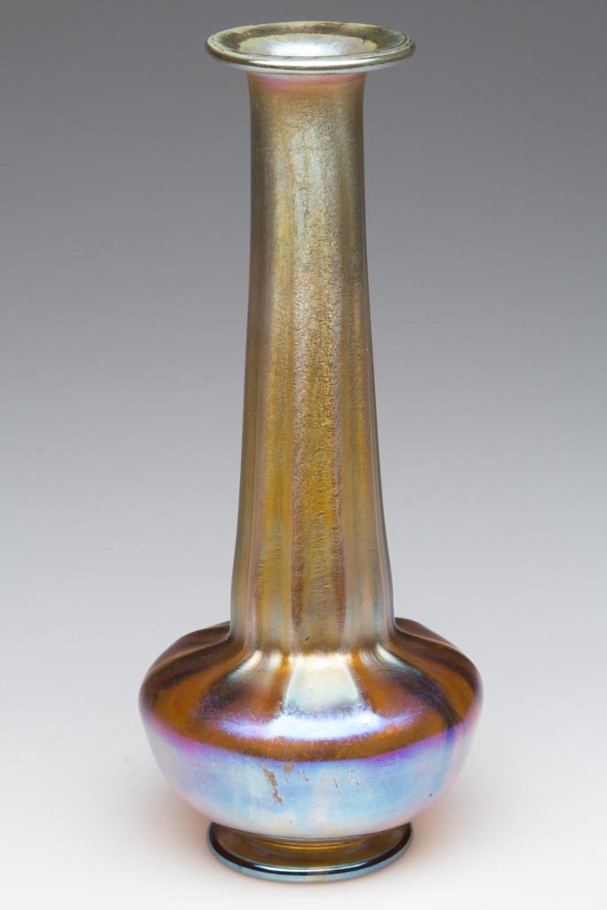 TIFFANY FAVRILE RIB-OPTIC VASE: TIFFANY FAVRILE RIB-OPTIC VASE, gold iridescent, tall tapering neck above a low compressed body, raised on an applied foot, signed "L. C. Tiffany Favrile 1834" around the polished pontil mark. Louis C