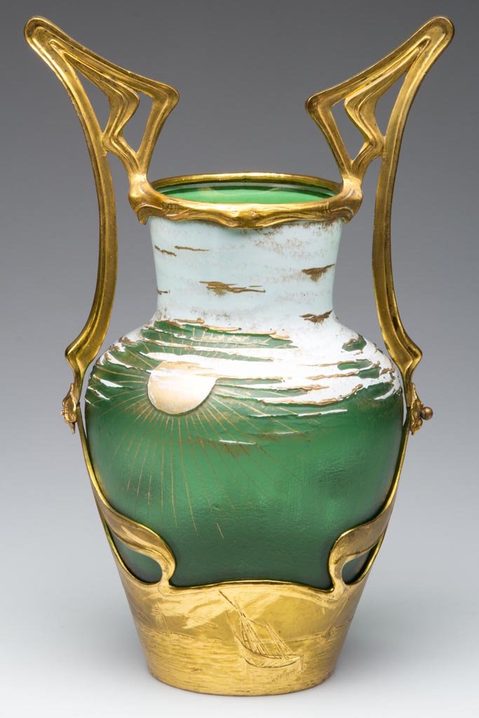 MOSER ART NOUVEAU ACID CUT-BACK VASE: MOSER ART NOUVEAU ACID CUT-BACK VASE, white to green with gilding, vase depicting clouds and a sunset, original gilt-metal frame with a lighthouse and boats at lower edge. Late 19th century. 11 1/2" H