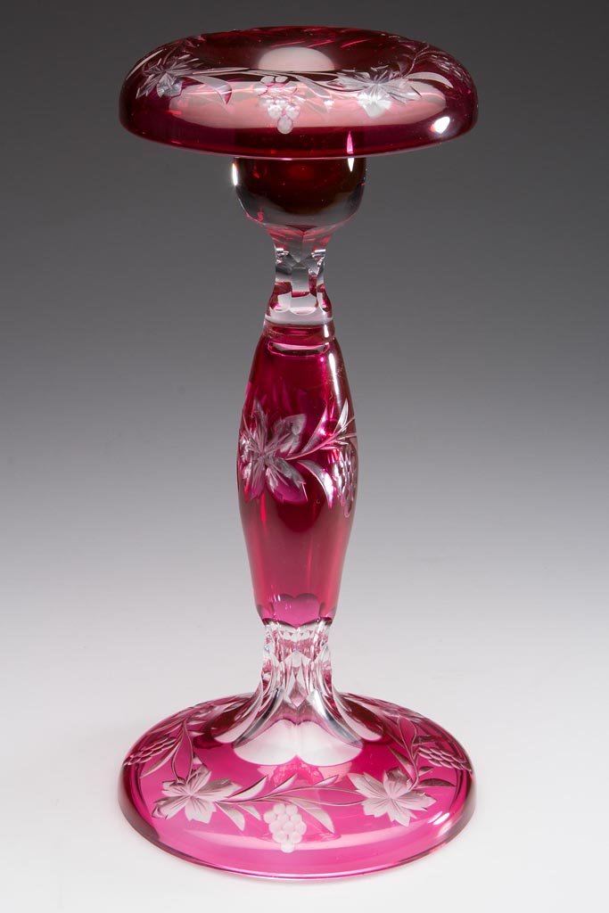 VINTAGE PATTERN CUT OVERLAY CANDLESTICK: VINTAGE PATTERN CUT OVERLAY CANDLESTICK, ruby to colorless, rolled-over socket rim, hollow stand and foot each with a grapevine cutting, cut facets above and below stem, polished table ring. 20th cent