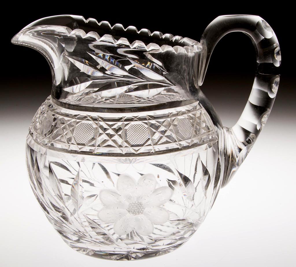 AMERICAN CUT AND ENGRAVED GLASS WATER PITCHER: AMERICAN CUT AND ENGRAVED GLASS WATER PITCHER, colorless, fine point octagons and cut miters band between engraved floral pattern, handle with cut punties. Possibly H. C. Fry Glass Co. Early 20th cent
