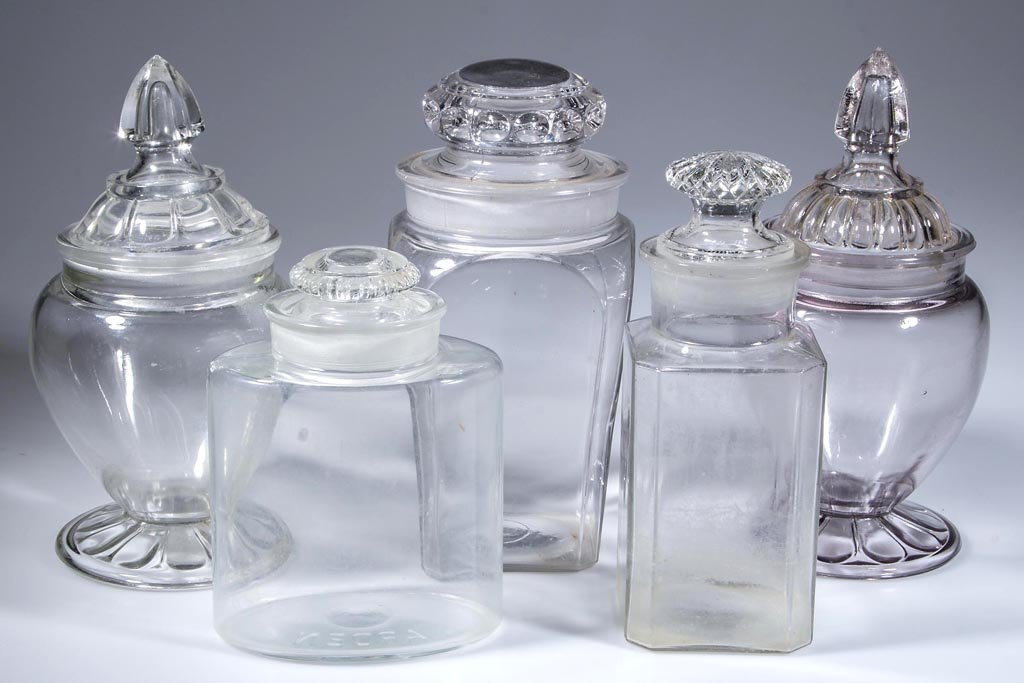 ASSORTED PRESSED GLASS APOTHECARY JARS, LOT OF FIVE: ASSORTED PRESSED GLASS APOTHECARY JARS, LOT OF FIVE, colorless, each with ground stopper, two slightly ill-fitting. First half 20th century. 7 1/2" to 10 1/2" HOA. Provenance: From a Midwestern estate