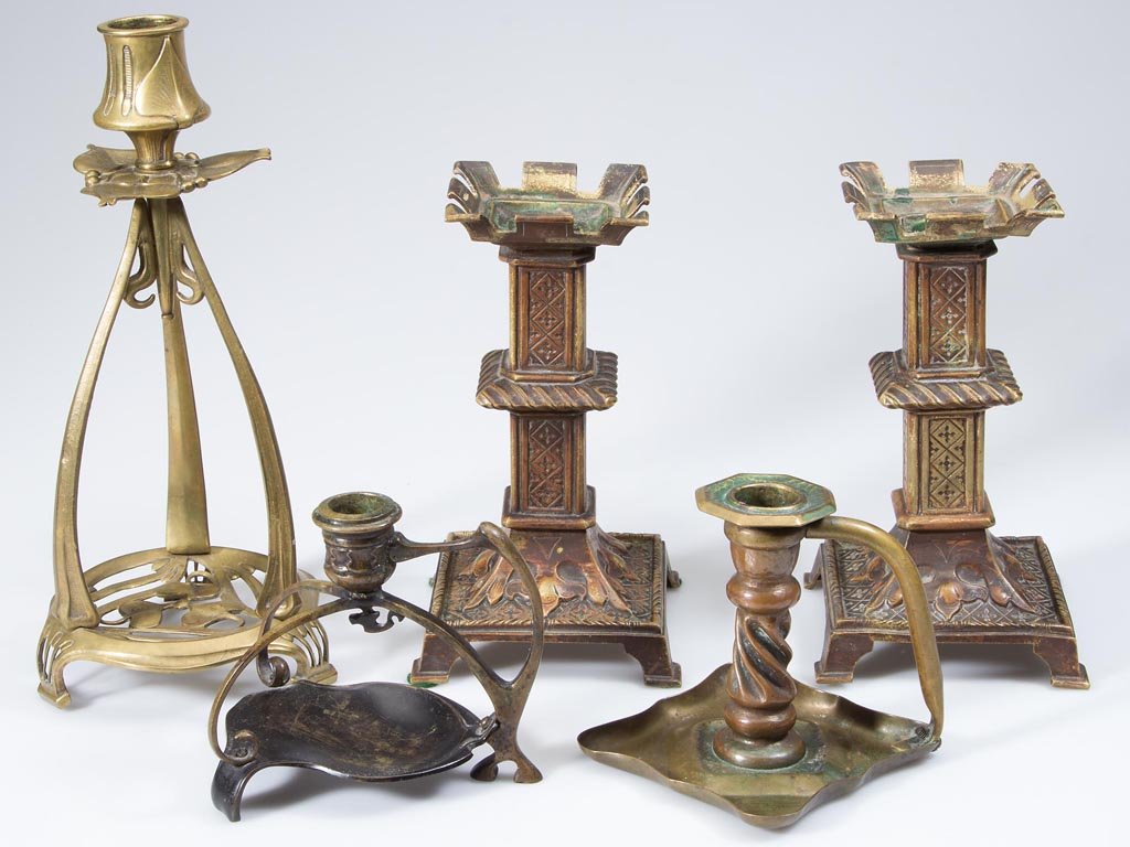 ASSORTED ART NOUVEAU AND ARTS & CRAFTS BRASS: ASSORTED ART NOUVEAU AND ARTS & CRAFTS BRASS CANDLEHOLDERS, LOT OF FIVE, including a pair and two with handles. Late 19th/first quarter 20th century. 4 1/4" to 10 3/4" H. Provenance: Collection of the