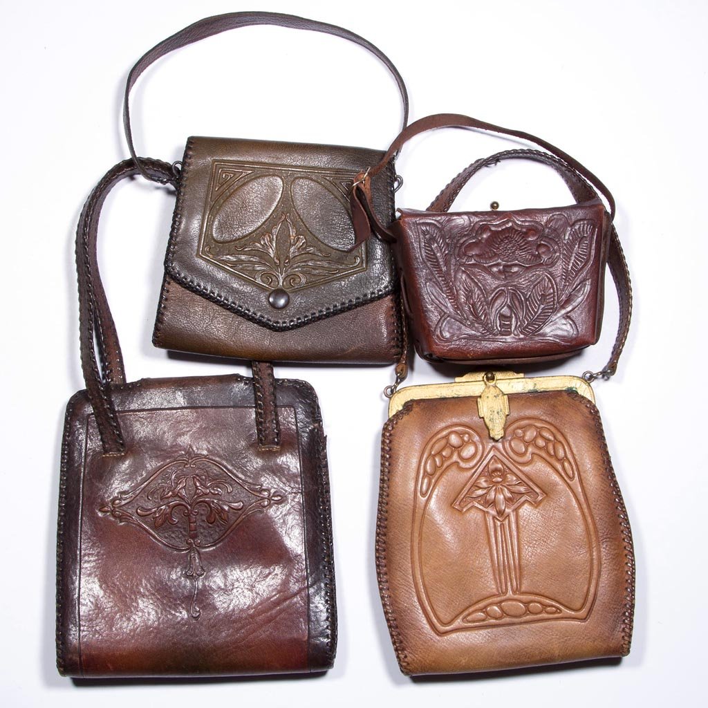 ARTS & CRAFTS TOOLED-LEATHER PURSES, LOT OF FOUR: ARTS & CRAFTS TOOLED-LEATHER PURSES, LOT OF FOUR, each with original straps and art nouveau floral decoration. First half 20th century. 4" to 7 1/2" L. Provenance: From the collection of Charles and G