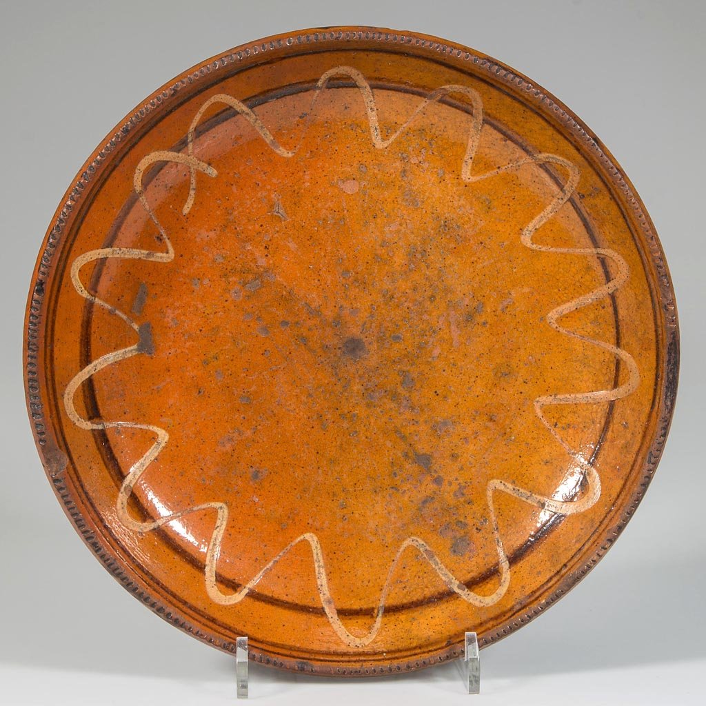 HAGERSTOWN, MARYLAND (ATTRIBUTED) SLIP-DECORATED: HAGERSTOWN, MARYLAND (ATTRIBUTED) SLIP-DECORATED EARTHENWARE / REDWARE PLATE / DISH, lead-glazed, shallow form with rouletted rim. Slipped arch decoration over two manganese rings. Circa 1800-1820. 1