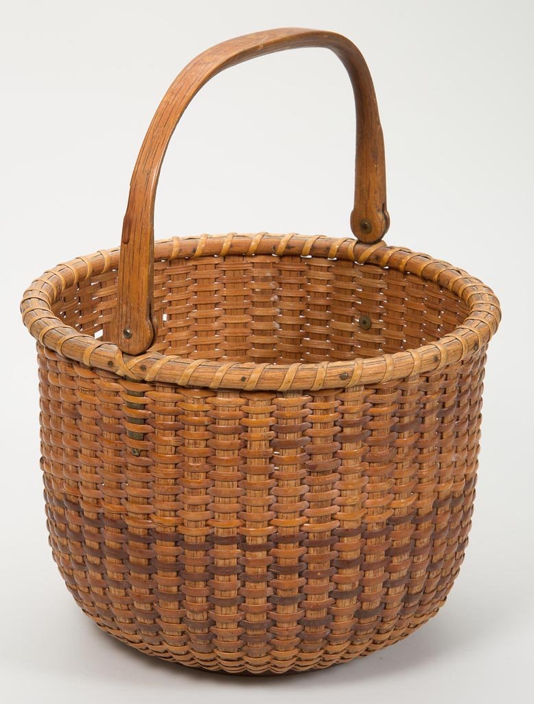 NANTUCKET LIGHTSHIP BASKET: NANTUCKET LIGHTSHIP BASKET, splint, cane, mixed woods, brass, and copper, the elegant circular form with carved swinging handle, contrasting weaving, wrapped rim, and turned wooden bottom. In old dry