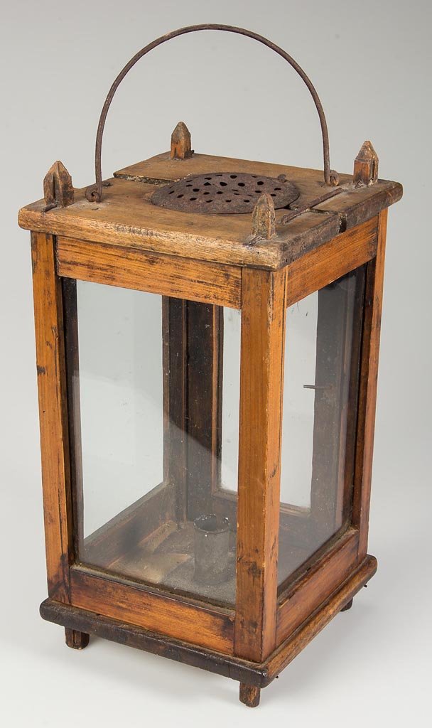 WOOD, SHEET-IRON, AND GLASS CANDLE LANTERN: WOOD, SHEET-IRON, AND GLASS CANDLE LANTERN, square-frame form with single hinged door, corner posts mortised through the top and base, perforated sheet-iron cap and bail handle. 19th century. 12" H to