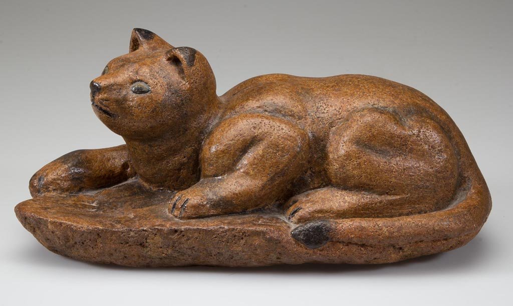 MARIE GOOD (FLOYD CO., VIRGINIA) CARVED AND PAINTED CAT: MARIE GOOD (FLOYD CO., VIRGINIA) CARVED AND PAINTED CAT FIGURE, soapstone, the reclining figure with painted highlights resting on base. 20th century/21st century. 4 3/4" HOA, 10 1/2" LOA. Provenance: