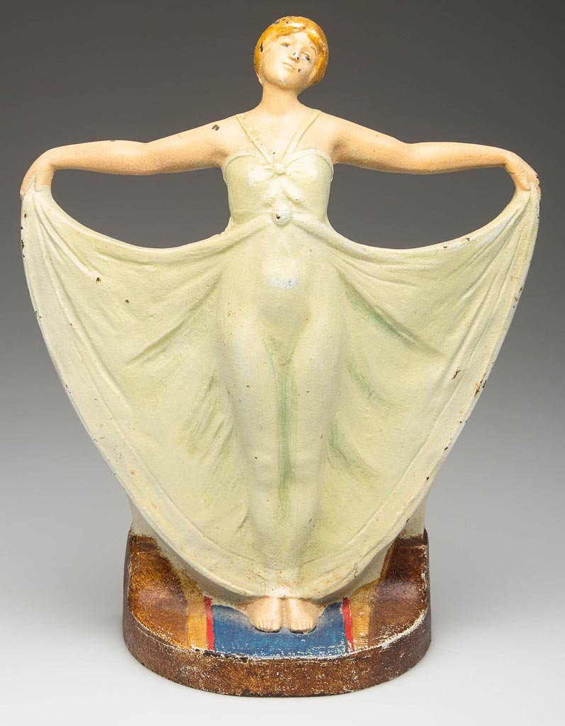 ART DECO GIRL CAST-IRON DOORSTOP: ART DECO GIRL CAST-IRON DOORSTOP, the female figure with outstretched arms grasping her flowing gown, impressed "1251 reverse side. Original painted surface. First quarter 20th century. 9 1/4" H, 7 1/