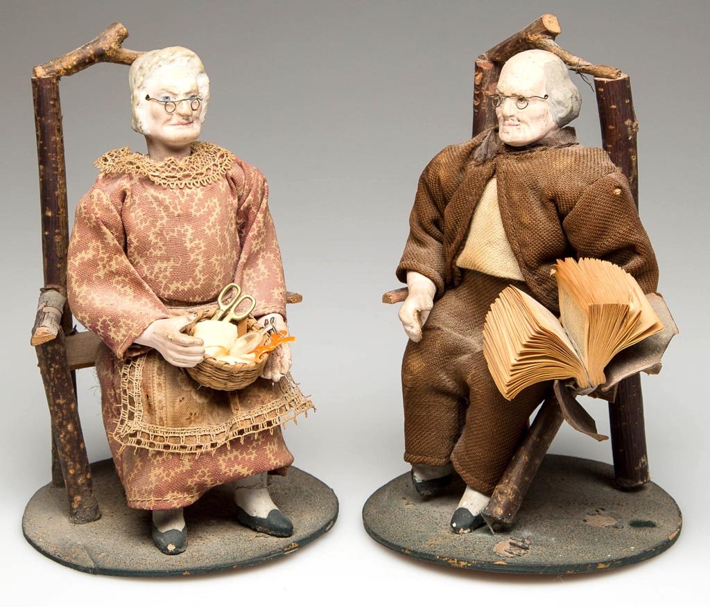 PAIR OF GERMAN PAPIER-MACHE NODDING FIGURES: PAIR OF GERMAN PAPIER-MACHE NODDING FIGURES, comprising male and female examples depicting an elderly couple in period attire, each seated in a stick-made chair resting on a circular green-painted bas
