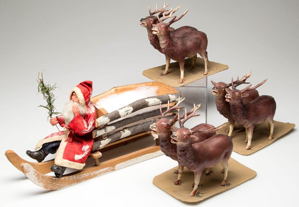JAPANESE CHRISTMAS HOLIDAY DECORATIONS: JAPANESE CHRISTMAS HOLIDAY DECORATIONS, comprising a wooden sleigh with cloth and papier-mache Santa Claus figure, pulled by six celluloid reindeer, labeled and embossed markings. First half 20th cent
