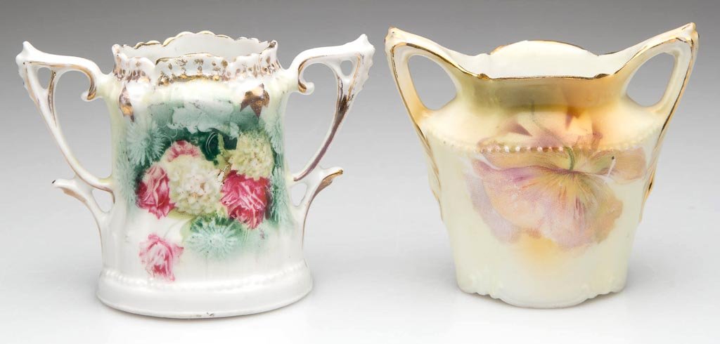 R. S. PRUSSIA PORCELAIN TOOTHPICK HOLDERS, LOT OF TWO: R. S. PRUSSIA PORCELAIN TOOTHPICK HOLDERS, LOT OF TWO, one with a waisted neck and two flaring handles; the other with Art Nouveau-style handles below a scalloped rim each decorated with flowers. Red