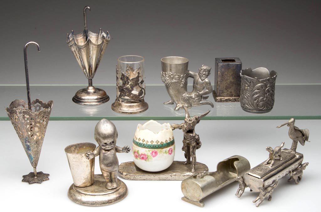 ASSORTED METAL TOOTHPICK HOLDERS, LOT OF TEN: ASSORTED METAL TOOTHPICK HOLDERS, LOT OF TEN, including silver-plate parasols and Kewpie. 20th century. 1" to 6 1/4" HOA. Provenance: From the collection of Edward Cooke.