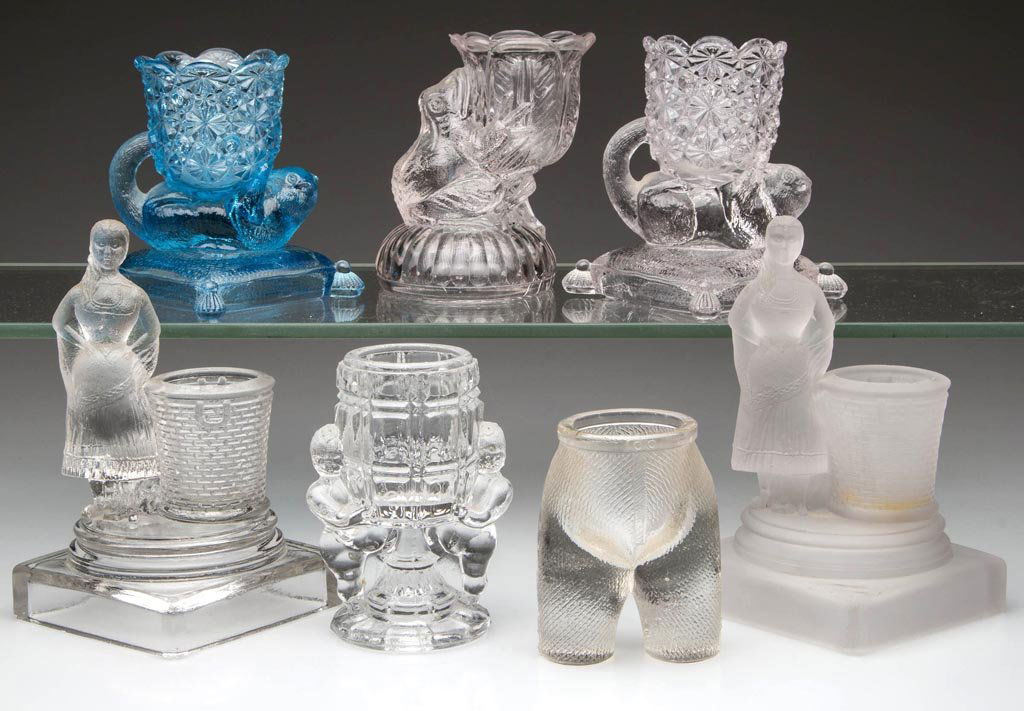 ASSORTED FIGURAL GLASS TOOTHPICK HOLDERS, LOT OF SEVEN: ASSORTED FIGURAL GLASS TOOTHPICK HOLDERS, LOT OF SEVEN, colorless and blue, including two Pretty Maiden, one frosted, and a Frog on a Pedestal. Late 19th/early 20th century. 3" to 5 1/2" H. Provenance