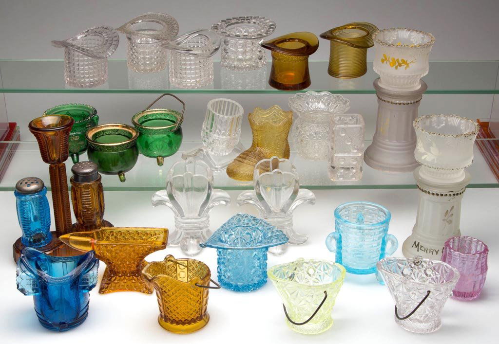 ASSORTED FIGURAL GLASS TOOTHPICK HOLDERS, LOT OF 26: ASSORTED FIGURAL GLASS TOOTHPICK HOLDERS, LOT OF 26, various colors, including two jardinières on pedestals, and a vaseline (uranium) Daisy and Button Coal Hod. Late 19th/early 20th century. 6" HOA.