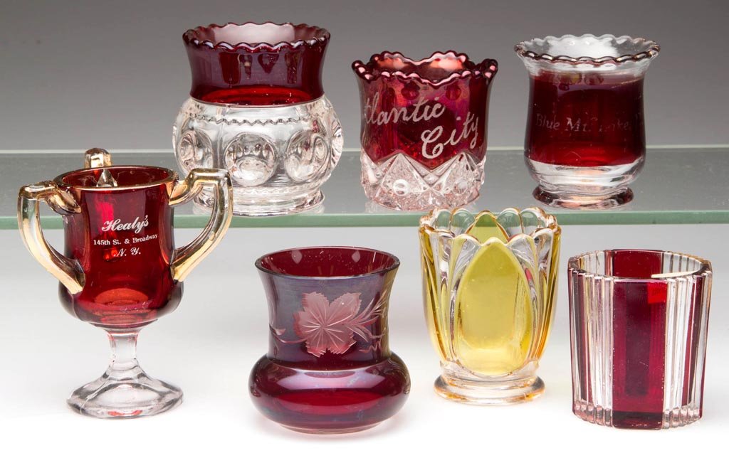 ASSORTED STAINED EAPG TOOTHPICK HOLDERS, LOT OF SEVEN: ASSORTED STAINED EAPG TOOTHPICK HOLDERS, LOT OF SEVEN, colorless, comprising six ruby examples and an amber example. Fourth quarter 19th century. 2 1/4" to 3 1/2" H. Provenance: From the collection of