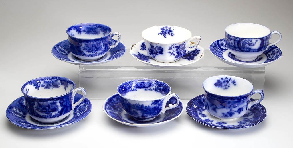 ENGLISH IRONSTONE POTTERY FLOW BLUE CUP AND SAUCER: ENGLISH IRONSTONE POTTERY FLOW BLUE CUP AND SAUCER SETS, LOT OF SIX, including examples by Ridgways, Johnson Brothers, Wood and Sons, etc. Circa 1880-1920. Cups 2 1/2" H, saucers 6" D. Provenance: Pro