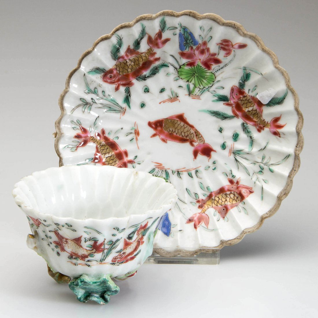 CHINESE EXPORT PORCELAIN LOTUS-FORM CUP AND SAUCER: CHINESE EXPORT PORCELAIN LOTUS-FORM CUP AND SAUCER, both with applied flowers and vines, painted in the Famille Rose palette with goldfish among lotus and other water blossoms. Mid 18th century. Cup 1