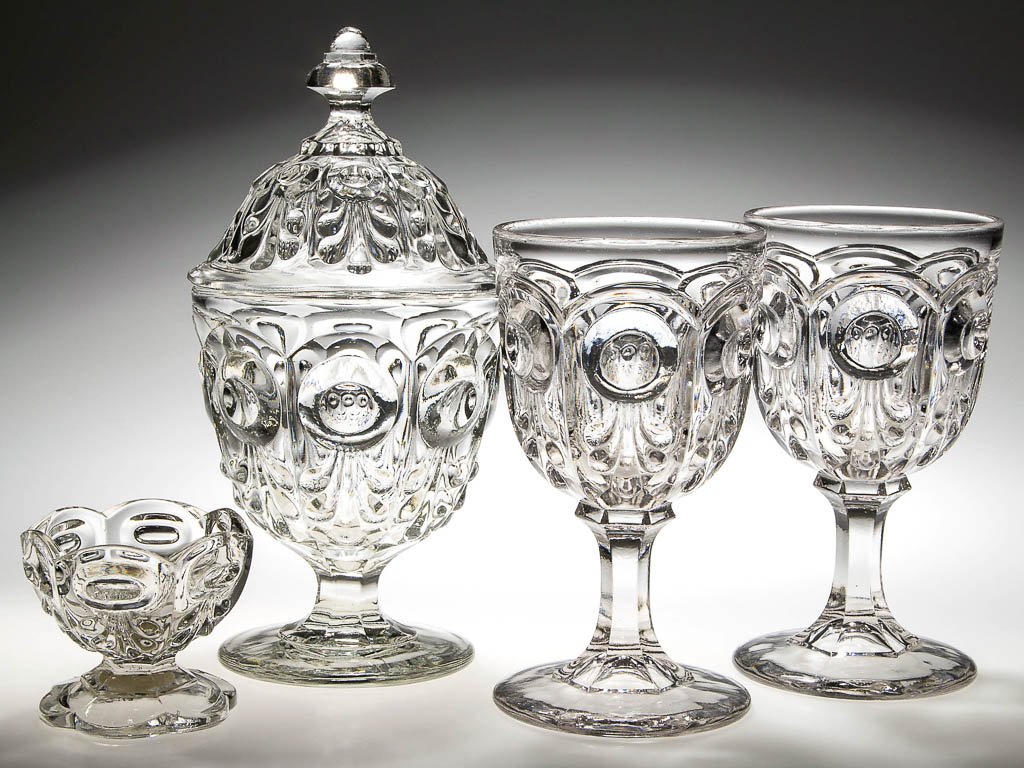 BULL'S EYE WITH FLEUR DE LYS TABLE ARTICLES, LOT OF: BULL'S EYE WITH FLEUR DE LYS TABLE ARTICLES, LOT OF FOUR, colorless lead glass, comprising two goblets, a covered sugar bowl, and open salt. Third quarter 19th century. 2 5/8" to 9" HOA. Provenance: C