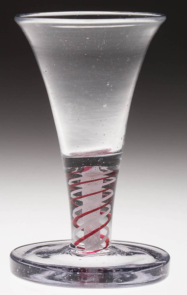 FREE-BLOWN COLORED AND OPAQUE-TWIST STEM FIRING GLASS: FREE-BLOWN COLORED AND OPAQUE-TWIST STEM FIRING GLASS, colorless non-lead glass with gray tint, trumpet bowl raised on a stem containing pairs of red and white heavy spiral threads outside loose verti