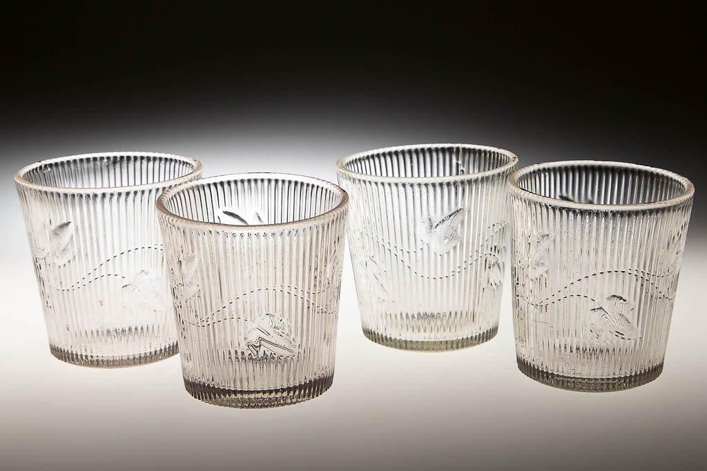 RIBBED IVY WHISKEY TUMBLERS, LOT OF FOUR: RIBBED IVY WHISKEY TUMBLERS, LOT OF FOUR, colorless lead glass, each with a slight tint. Third quarter 19th century. 2 5/8" to 2 7/8" H, 2 1/2" to 2 5/8" D rim. Provenance: Property from the Trestle B
