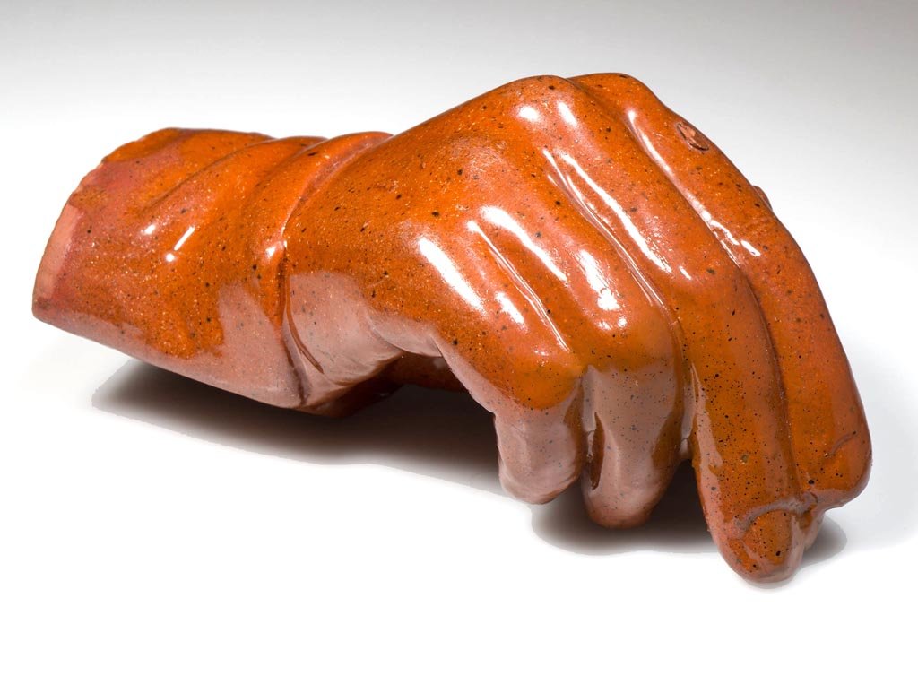 AMERICAN EARTHENWARE / REDWARE MOLDED FIGURAL: AMERICAN EARTHENWARE / REDWARE MOLDED FIGURAL PAPERWEIGHT, lead glazed, hand form holding a pencil, stamped "PATENT" to underside. Probably Pennsylvania. Second half 19th century. 2" H, 4 1/2" L. Prov