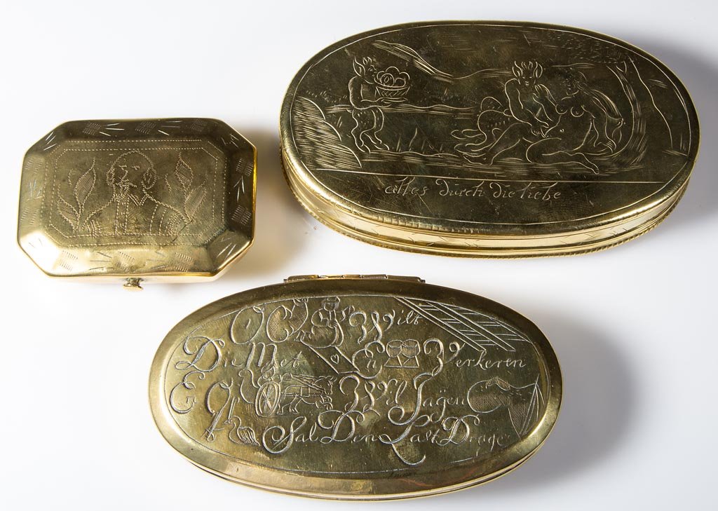DUTCH ENGRAVED BRASS SNUFF / TOBACCO BOXES, LOT OF TWO: DUTCH ENGRAVED BRASS SNUFF / TOBACCO BOXES, LOT OF TWO, each of oval form with hinged lid, one featuring occupational imagery, the other with erotic scenes, each with German inscriptions. Together wit