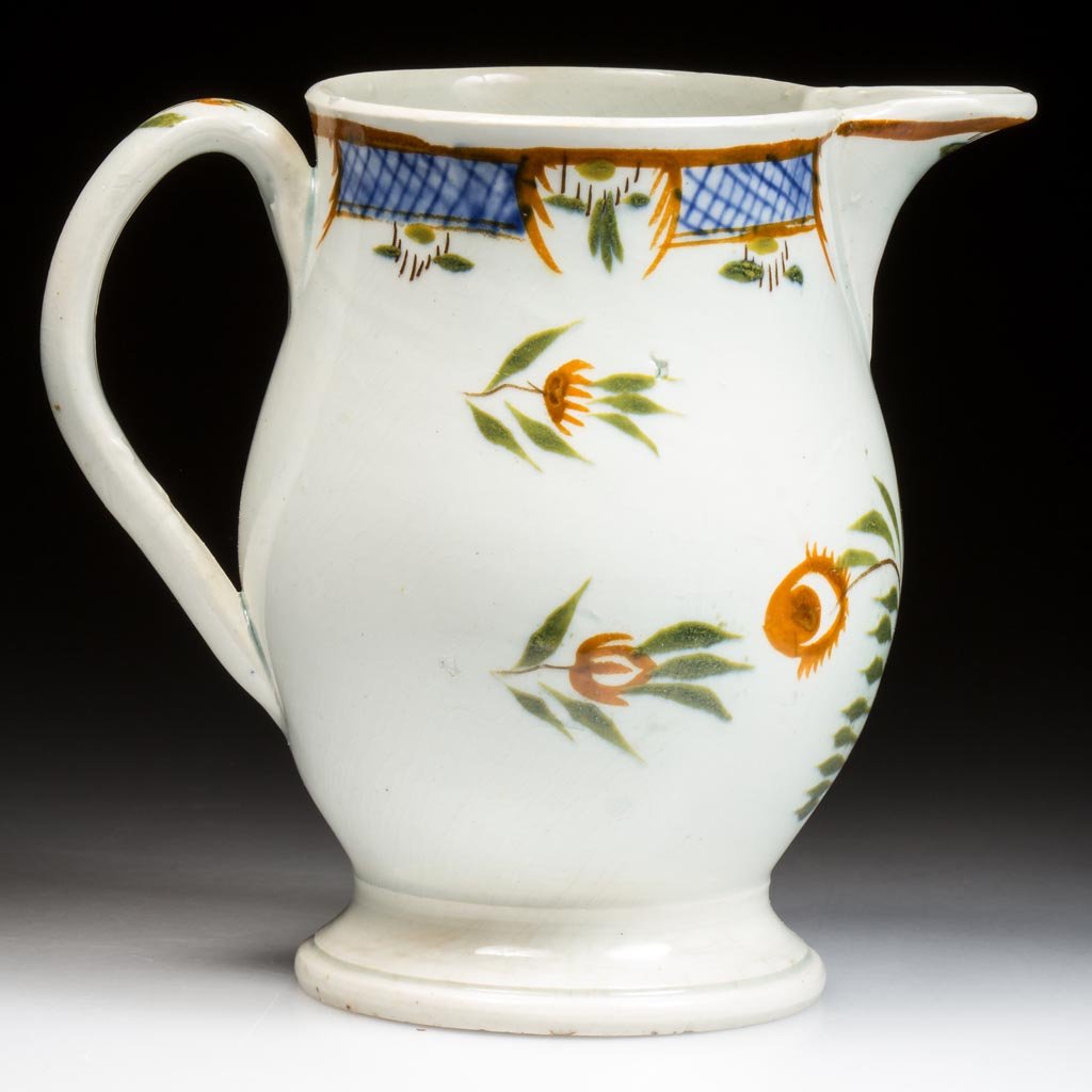 ENGLISH STAFFORDSHIRE PEARLWARE POTTERY SMALL CIDER JUG: ENGLISH STAFFORDSHIRE PEARLWARE POTTERY SMALL CIDER JUG, baluster form on a low-spreading foot and with everted spout and arching handle, painted with stylized foliate designs in ocher and green, unde