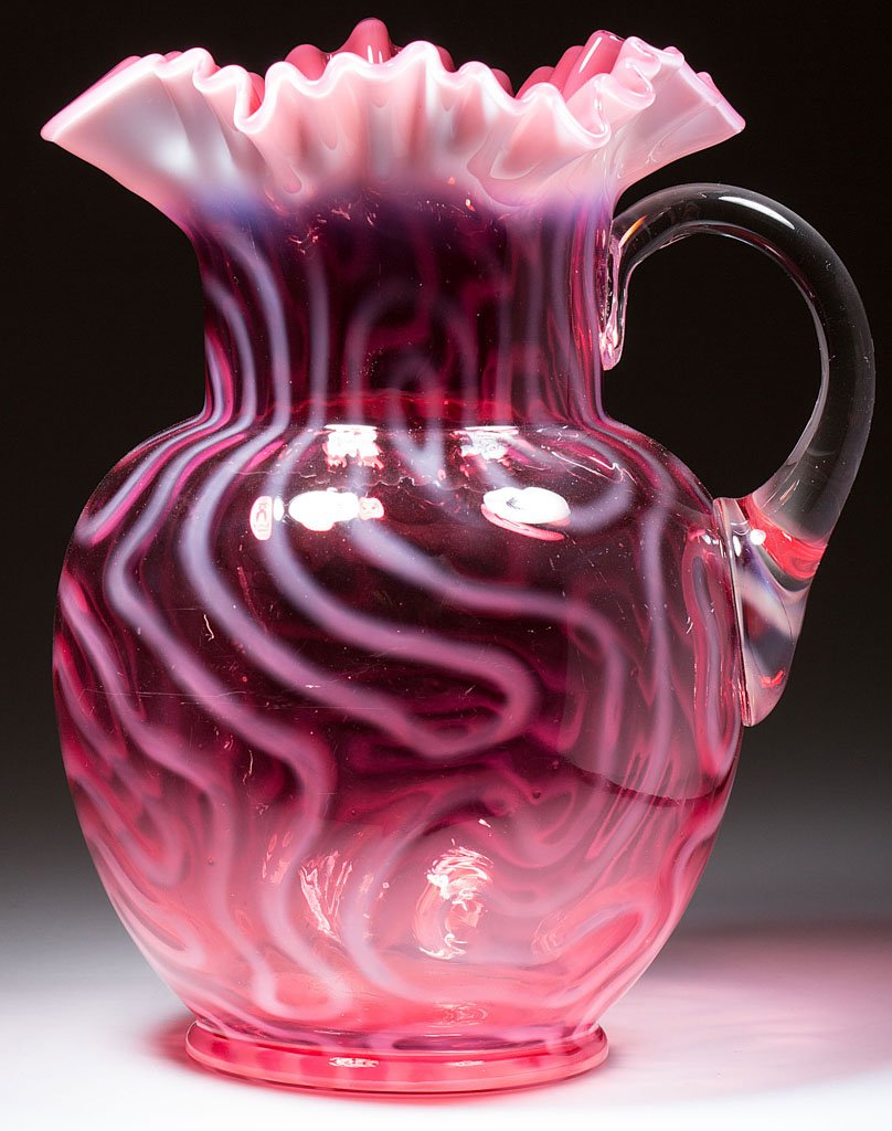 SWIRLING MAZE WATER PITCHER: SWIRLING MAZE WATER PITCHER, deep cranberry opalescent, bulbous form with star-crimped rim, applied colorless handle. Jefferson Glass Co. Circa 1905. 9 3/4" HOA. Literature: Pattern as Heacock/Elmore
