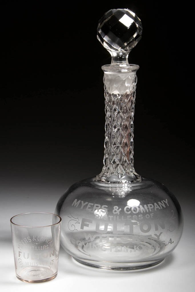 FULTON WHISKEY GLASS ADVERTISING ITEMS, LOT OF TWO: FULTON WHISKEY GLASS ADVERTISING ITEMS, LOT OF TWO, colorless with etched lettering, comprising a back-bar decanter with original stopper and a shot glass. Myers & Co. Distillers, Covington, Kentucky.