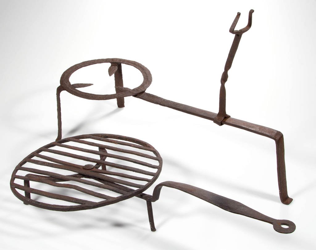 WROUGHT-IRON HEARTH ARTICLES, LOT OF TWO: WROUGHT-IRON HEARTH ARTICLES, LOT OF TWO, comprising a trivet with adjustable fork-like support, raised on three legs with slightly flared feet, and a rotating gridiron with blade-like handle terminat