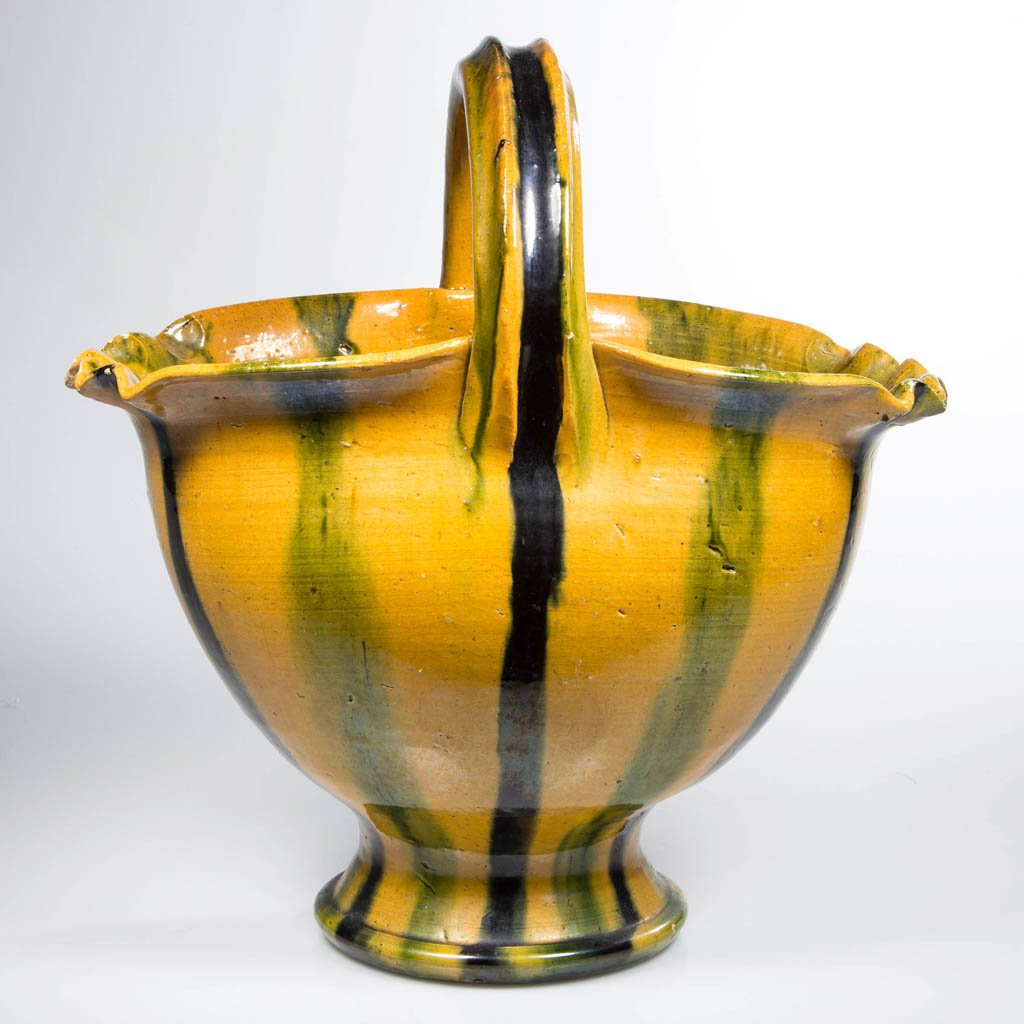 NORTH CAROLINA ART POTTERY MULTI-GLAZE BASKET: NORTH CAROLINA ART POTTERY MULTI-GLAZE BASKET, oval form with pie-crimped end rims, deeply grooved arched handle, raised on a flared foot, unmarked. Possibly Arthur Ray Cole's Rainbow Pottery, Sanford