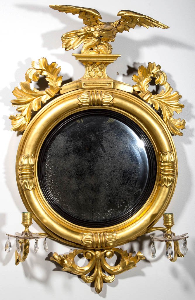 FEDERAL OR REGENCY GILTWOOD DIMINUTIVE GIRANDOLE WALL: FEDERAL OR REGENCY GILTWOOD DIMINUTIVE GIRANDOLE WALL MIRROR, spread-wing eagle above the convex mirror plate and two lower arms each fitted with a gilt-metal socket and cut-glass bobeche with prisms.