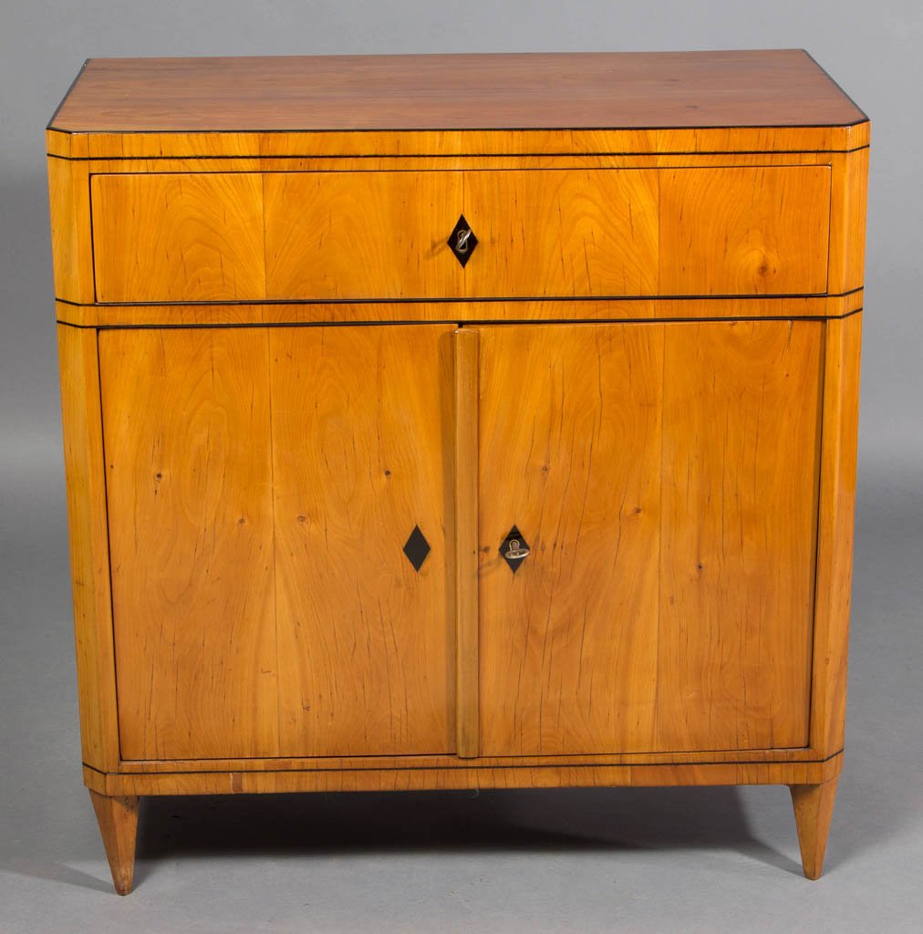 BIEDERMEIER CONSOLE CABINET: BIEDERMEIER CONSOLE CABINET, possibly beech, an elegant example with ebonized highlights, the rectangular top with canted corners over a conforming case with single full-length drawer over two hinged