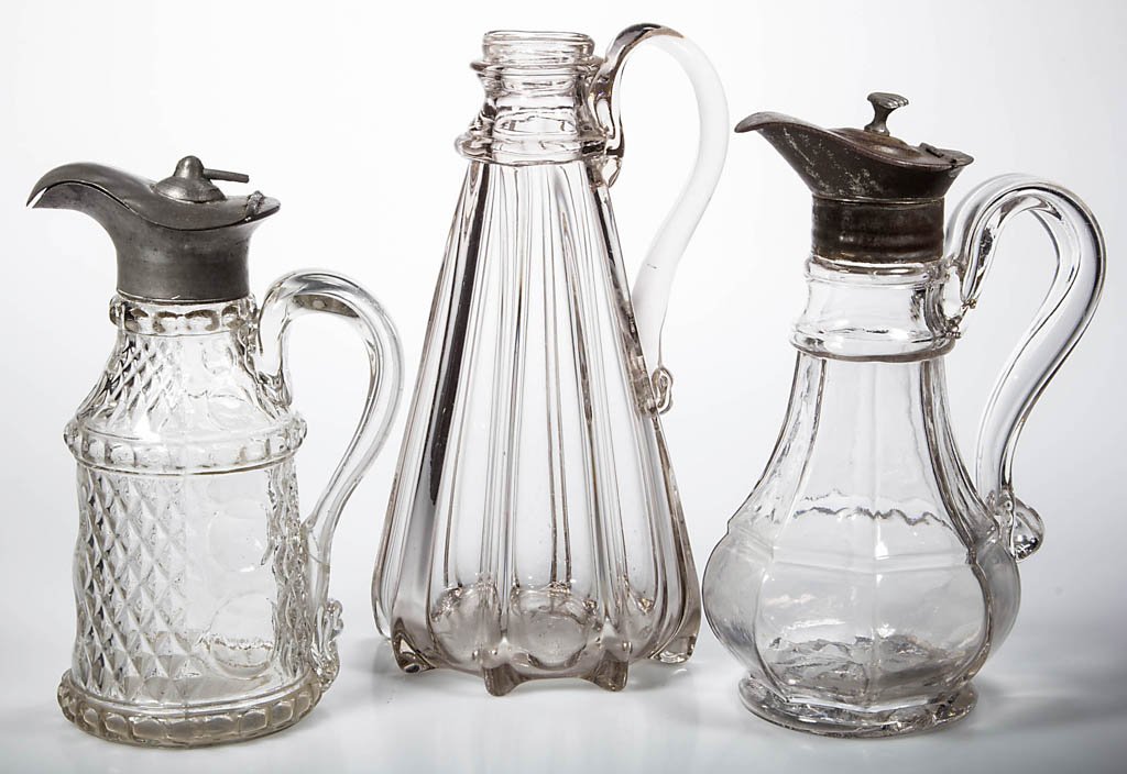 ASSORTED BLOWN-MOLDED MOLASSES CANS / SYRUP JUGS, LOT: ASSORTED BLOWN-MOLDED MOLASSES CANS / SYRUP JUGS, LOT OF THREE, colorless, comprising an Eight-Panel example and an Inverted Diamond and Thumbprint, each with applied hollow handle and appropriate hin