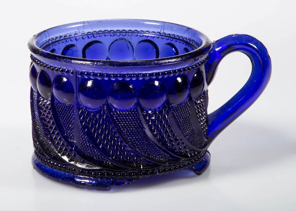 PRESSED LACY PEACOCK EYE MUSTARD JAR: PRESSED LACY PEACOCK EYE MUSTARD JAR, deep violet blue, jar with molded handle and rays and beaded ring under base, lacking cover. Boston & Sandwich Glass Co. Circa 1830-1845. 2" H, 2 3/4" D rim. Lite