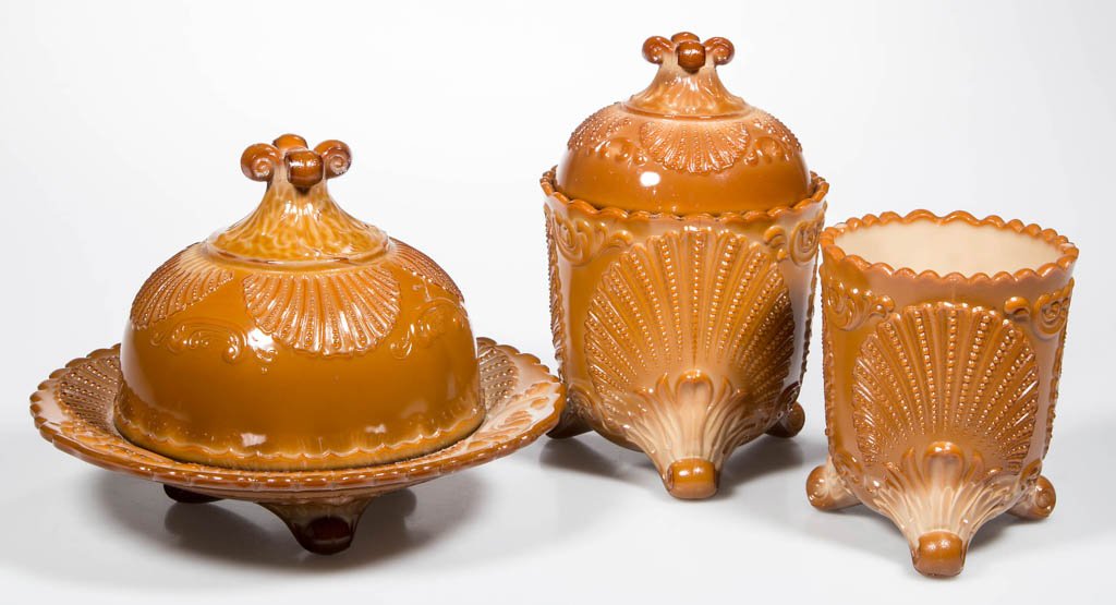GENEVA TABLE ARTICLES, LOT OF THREE: GENEVA TABLE ARTICLES, LOT OF THREE, chocolate, comprising a covered butter dish, a covered sugar, and a spooner. McKee Glass Co., Pittsburgh, PA. Circa 1902. Butter 5 1/2" HOA, 7 1/4" DOA.