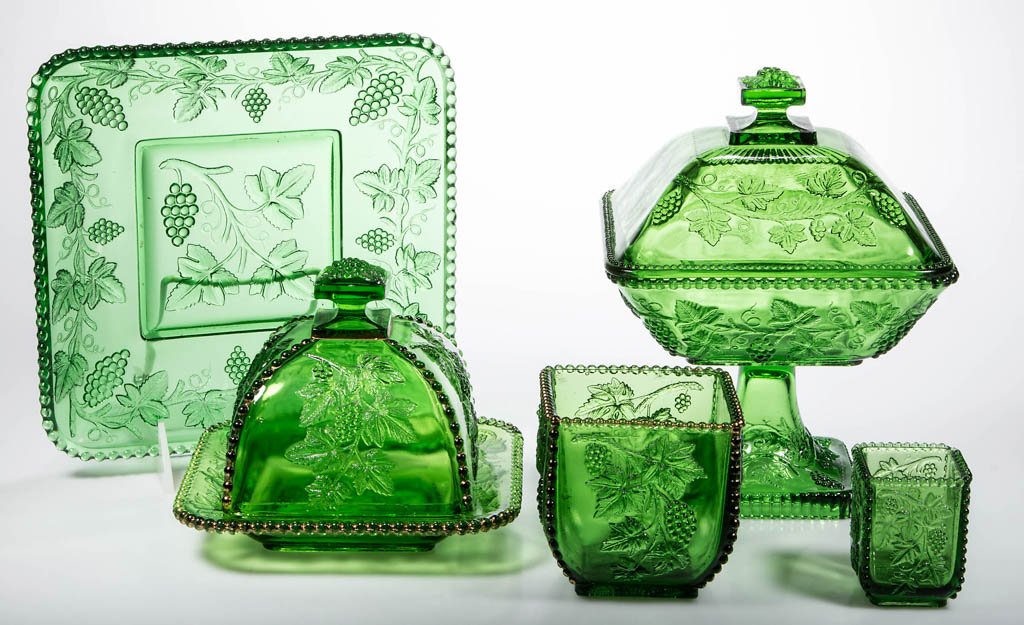 CALIFORNIA / BEADED GRAPE TABLE ARTICLES, LOT OF FIVE: CALIFORNIA / BEADED GRAPE TABLE ARTICLES, LOT OF FIVE, emerald green, comprising a butter dish, a covered compote, a spooner, a toothpick holder, and a square plate. U.S. Glass Co. Circa 1899. 2 1/2"