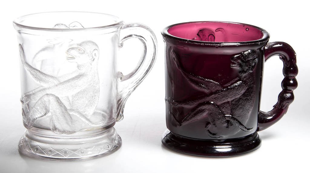 MONKEY MUGS, LOT OF TWO: MONKEY MUGS, LOT OF TWO, comprising an amethyst example with fancy handle and a colorless example with diamonds around the base. Fourth quarter 19th century. 3 3/8" and 3 3/4" H. Literature: Mordock/A