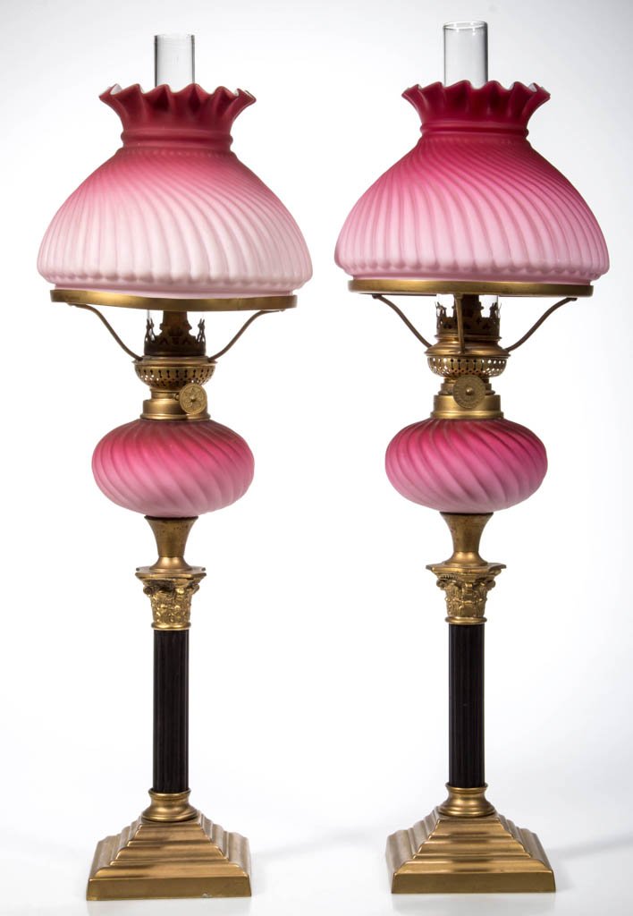 VERY RARE MATCHED PAIR OF SWIRLED RIB SATIN PEG OIL: VERY RARE MATCHED PAIR OF SWIRLED RIB SATIN PEG OIL LAMPS, cased deep raspberry to pink, each font supported by a brass and black ribbed pedestal weighted base. Matching umbrella shades. Period burner