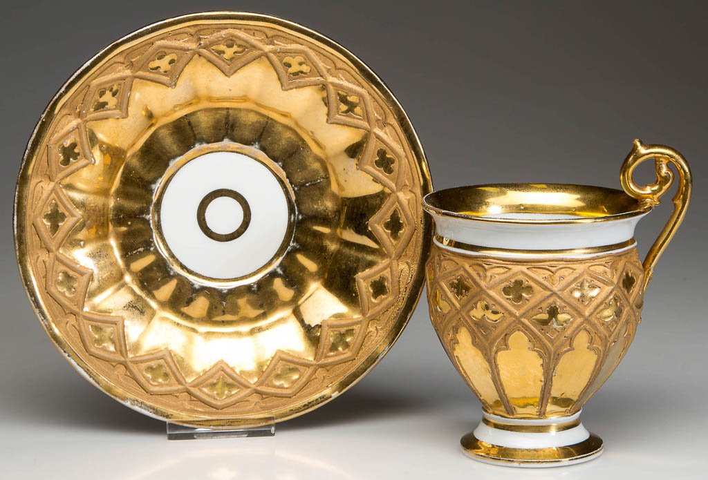 GERMAN MEISSEN PORCELAIN GOTHIC STYLE CABINET CUP AND: GERMAN MEISSEN PORCELAIN GOTHIC STYLE CABINET CUP AND SAUCER, baluster-form cabinet cup on foot, with curling acanthus leaf handle over the rim, the bodies molded with multiple panels, with raised gil