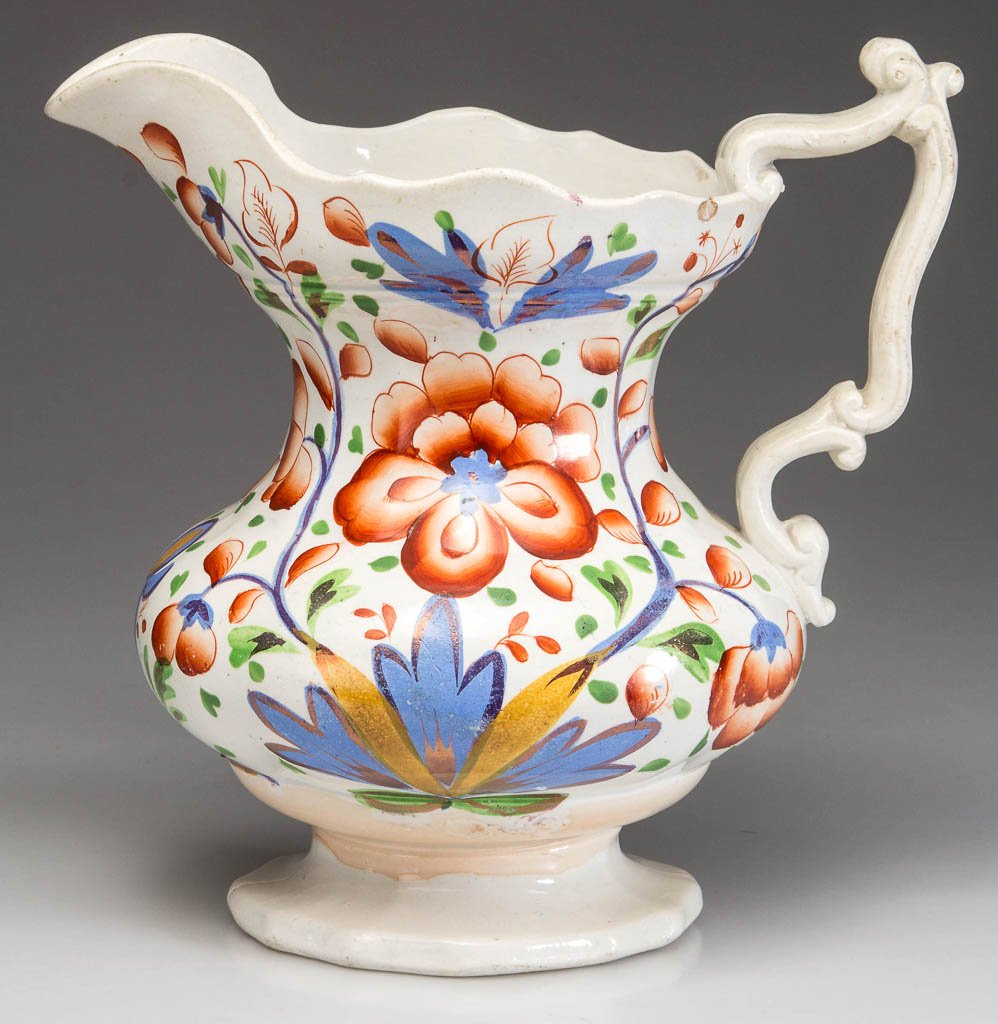 ENGLISH STAFFORDSHIRE POTTERY GAUDY WELSH SCALLOPED: ENGLISH STAFFORDSHIRE POTTERY GAUDY WELSH SCALLOPED PITCHER ON FOOT, ironstone low-bellied form with scalloped rim and foot, with elaborate scroll-form handle, painted in medium-blue, orange, ocher an