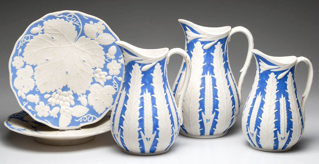 ENGLISH PARIAN PORCELAIN TABLE ARTICLES, LOT OF FIVE: ENGLISH PARIAN PORCELAIN TABLE ARTICLES, LOT OF FIVE, comprising three jugs in increasing size, of baluster form, with uplifted spouts, molded with wheat sheaves and grasses, on unglazed medium-blue g