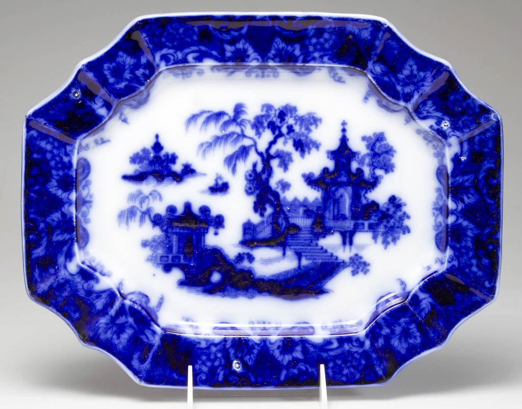 ENGLISH J. & G. ALCOCK IRONSTONE FLOW-BLUE "SCINDE": ENGLISH J. & G. ALCOCK IRONSTONE FLOW-BLUE "SCINDE" PATTERN PLATTER, rectangular with scallop-molded, canted corners, the rim with a deep-blue grapevine border, centering the Asian-inspired scene to t