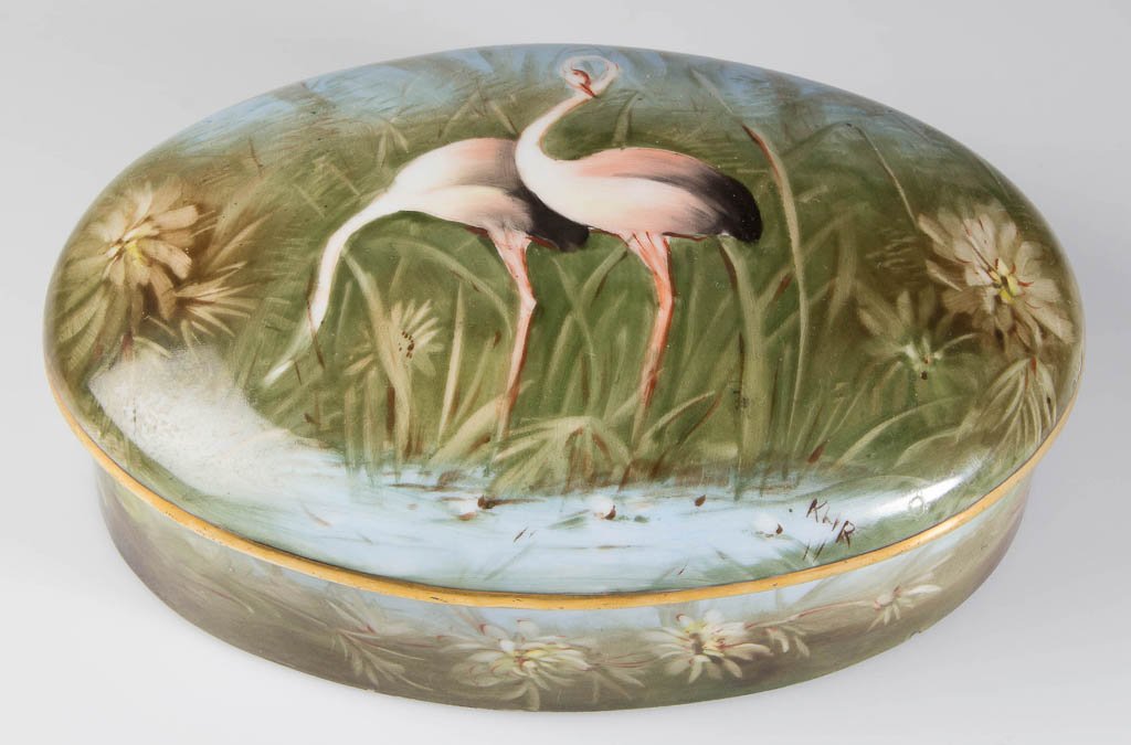 FRENCH PORCELAIN DRESSER BOX: FRENCH PORCELAIN DRESSER BOX, ovular box and lid, painted by KHR with a dense scene of pink flamingoes standing in a swamp, with orchids and grasses to the sides, under gilt line rims, the box base wi