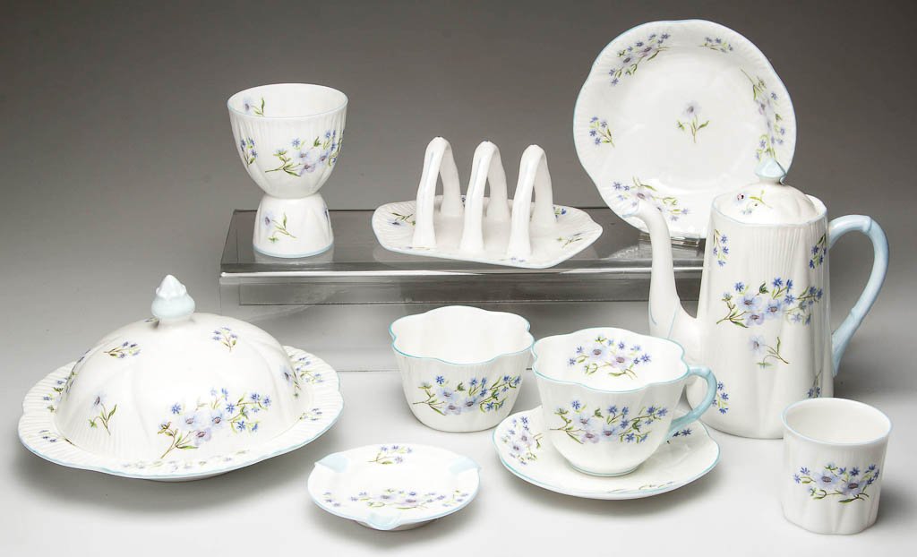 ENGLISH SHELLEY CHINA "DAINTY" SHAPE "BLUE ROCK": ENGLISH SHELLEY CHINA "DAINTY" SHAPE "BLUE ROCK" PATTERN TABLE ARTICLES, LOT OF NINE, white, printed with blue flowers on green stems, including a coffee pot with cover, a covered muffin dish, a toast
