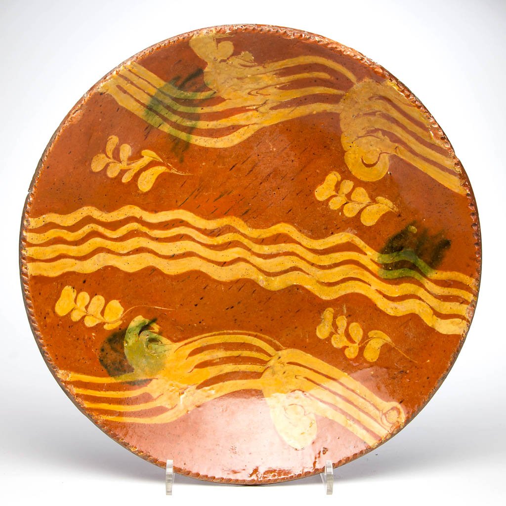 PENNSYLVANIA SLIP-DECORATED EARTHENWARE / REDWARE: PENNSYLVANIA SLIP-DECORATED EARTHENWARE / REDWARE CHARGER, lead-glazed, shallow form with coggled rim, center with strong yellow-slipped decoration and copper splotches. Second half 18th century. 2 1/